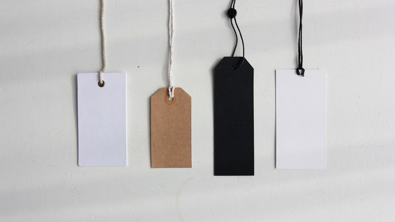 Four blank paper price tags on a white surface. Photo by Angèle Kamp on Unsplash.