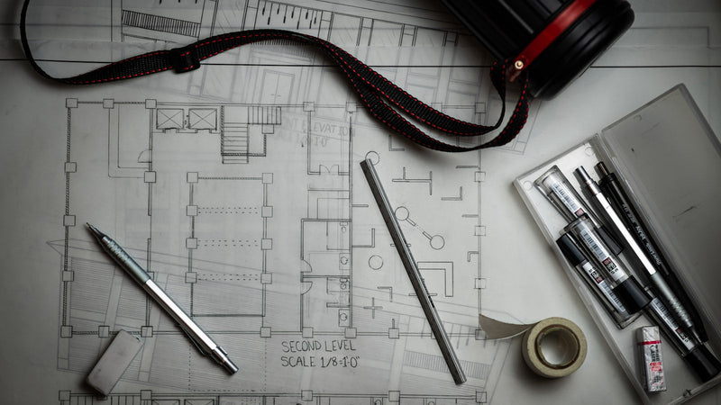 Architectural blueprint with drafting pencils and a ruler. Photo by Lucas Kepner on Unsplash.