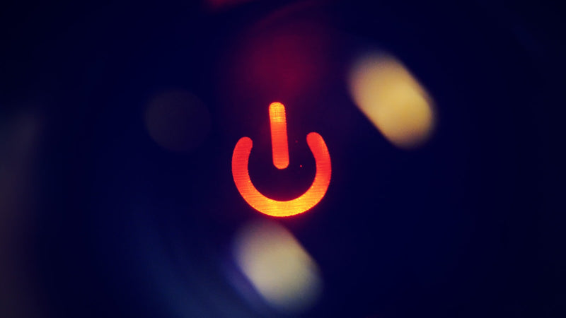 Glowing power button icon on a dark surface. Photo by Dima Shishkov on Unsplash.