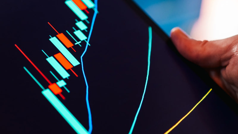 Tablet displaying a candlestick market chart. Photo by Jakub Zerdzicki on Unsplash.