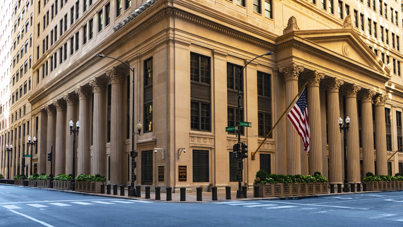Neoclassical bank building with columns and a flag. Photo by Joshua Woroniecki on Unsplash.