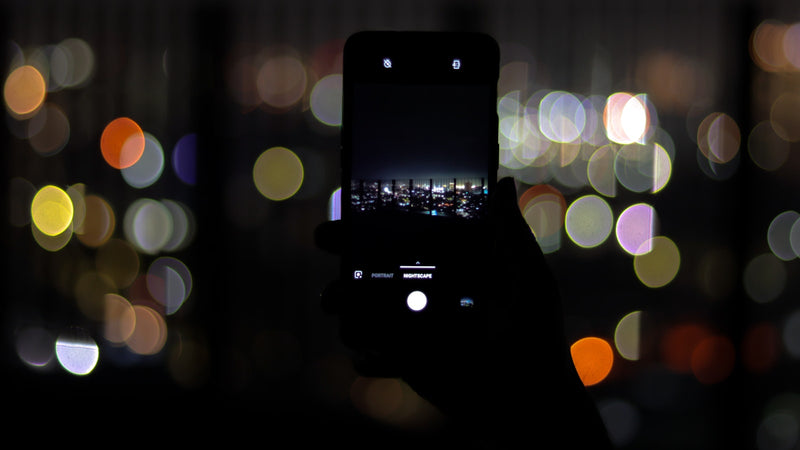 Smartphone held up against city lights at night. Photo by Lukenn Sabellano on Unsplash.