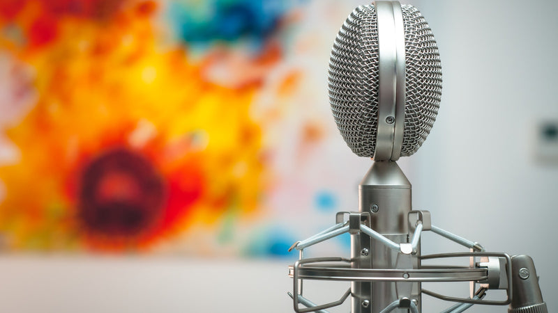 Studio microphone in front of a colourful background. Photo by Michal Czyz on Unsplash.