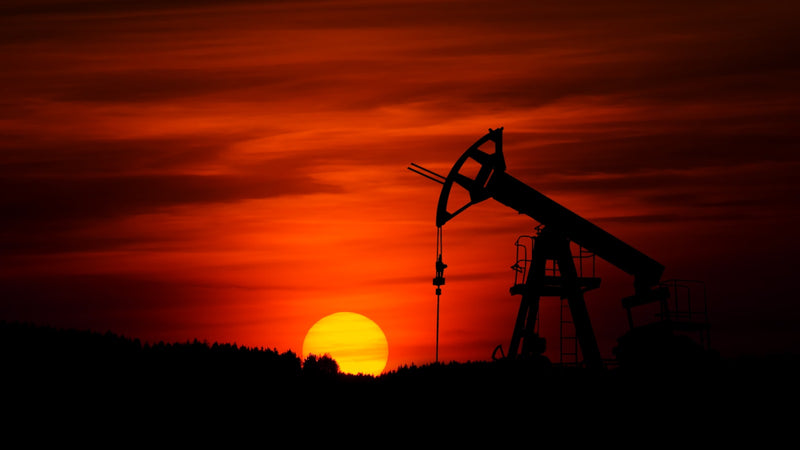 Oil pump jack silhouetted against a red sunset. Photo by Zbynek Burival on Unsplash.